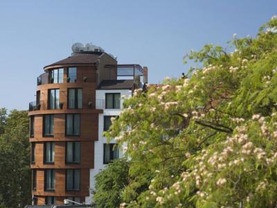 Hôtel moderne avec façade en bois à côté d'arbres verts en fleurs sous un ciel bleu