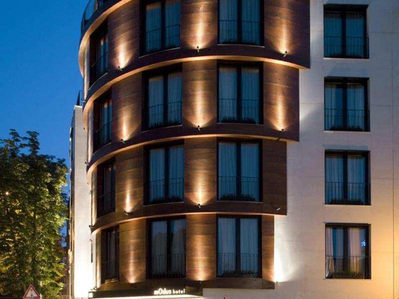 Nowoczesny budynek hotelowy z zaokrąglonymi narożnikami, oświetlony o zmierzchu.