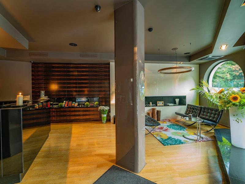 Jasne lobby hotelowe z drewnianymi podłogami, sofami i dużymi oknami.