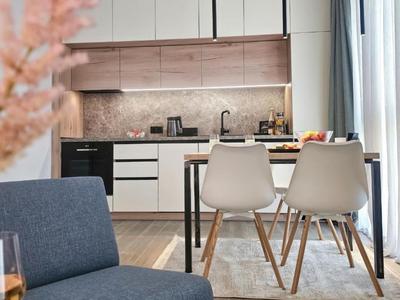 Cucina moderna open space con zona pranzo, sedie bianche e lavastoviglie integrata.