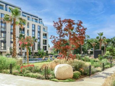 Complesso moderno con giardino curato, palme e aree relax sotto un cielo sereno