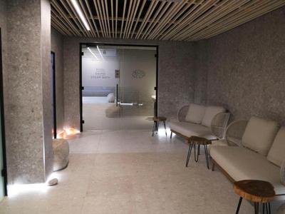 Modern hotel waiting room with gray walls, cozy sofas, and subdued lighting.