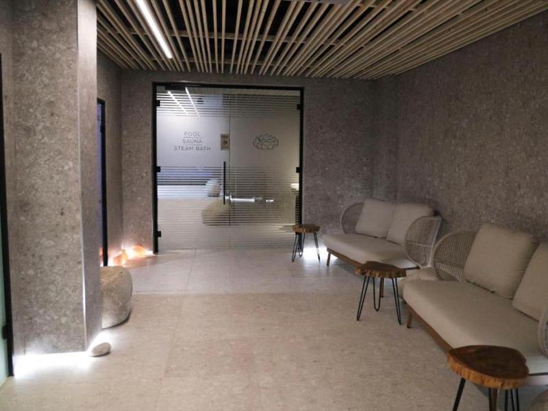 Modern hotel waiting room with gray walls, cozy sofas, and subdued lighting.