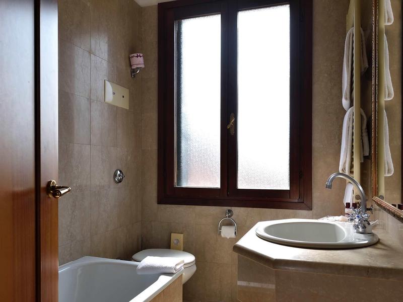 Small bathroom with window, sink, toilet, and towel holder.