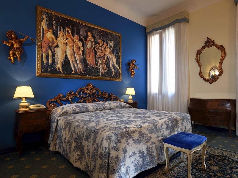 Elegant bedroom with large bed, blue wall, and decorative golden ornaments