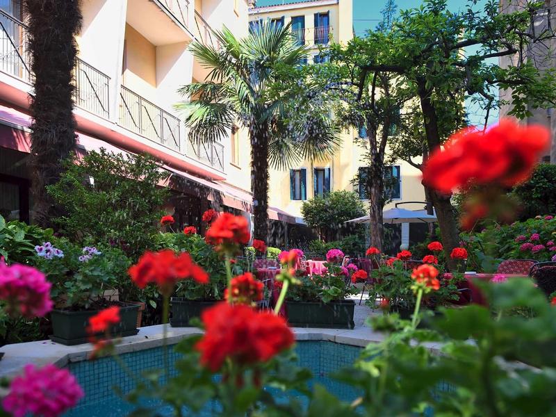 Colorful flower beds and palm trees in a sunny hotel courtyard.
