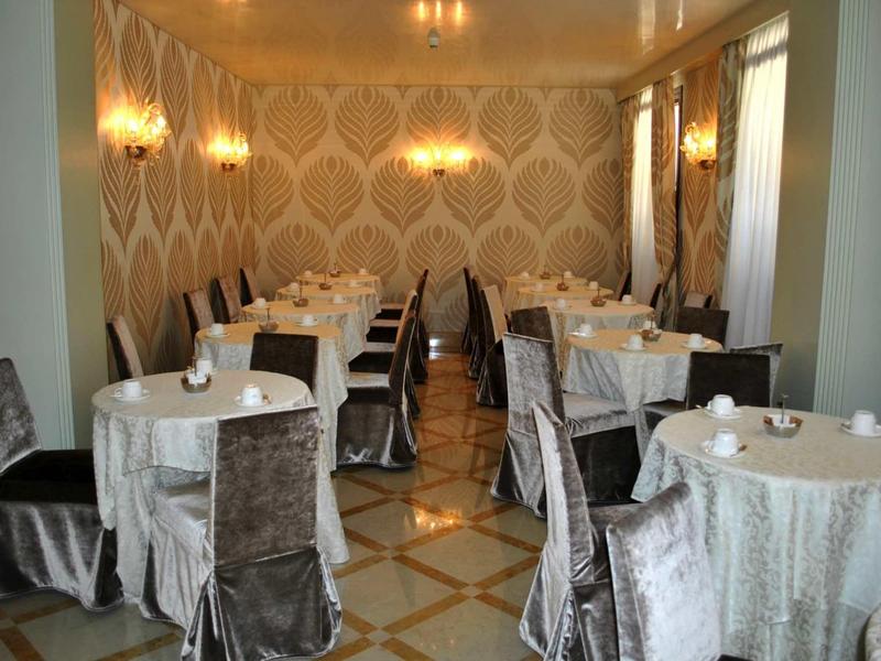 Elegant restaurant with round tables and silver chair covers in a stylish room.