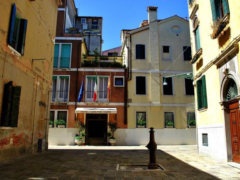 Courtyard with old buildings and a statue in the center under a blue sky.