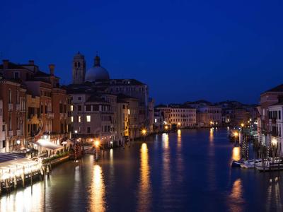 Blick auf einen beleuchteten Kanal mit historischen Gebäuden bei Nacht.