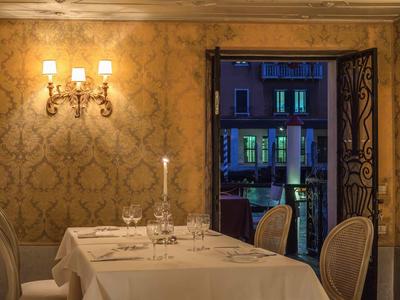 Elegant restaurant with set table and view of illuminated buildings outside.