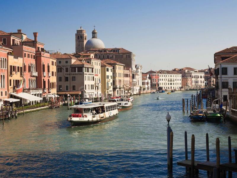 Historic canal in Venice with boats and buildings along the water under clear sky.