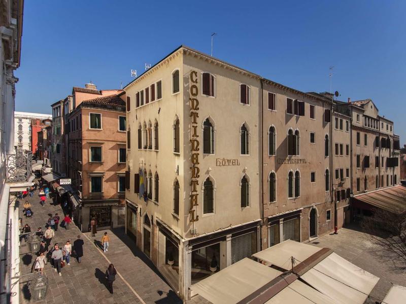 Street scene with historic building and cafés under clear sky