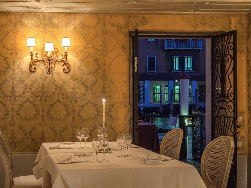 Elegant restaurant with set table and view of illuminated buildings outside.