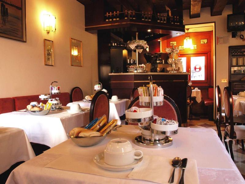 Salle de petit-déjeuner confortable avec tables dressées, café et pâtisseries dans un hôtel.