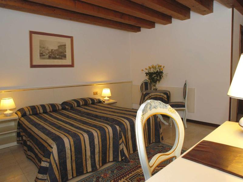 Chambre d'hôtel confortable avec lit double, plafond en bois, bureau et chaise.