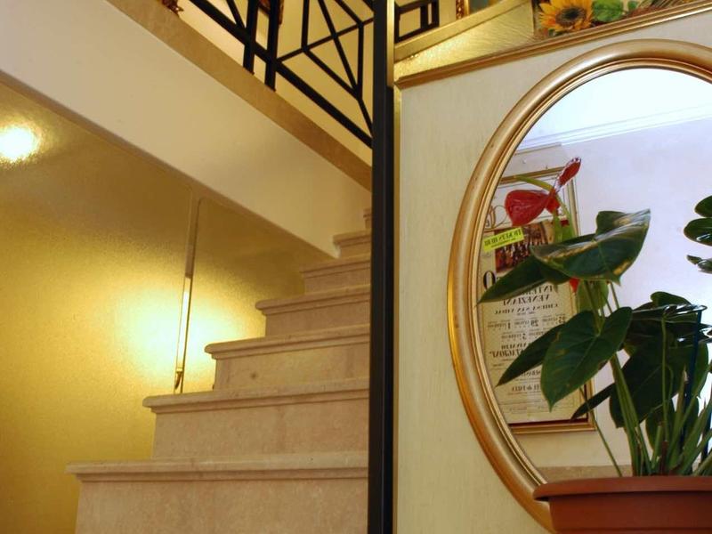 Escalier intérieur éclairé avec rampe élégante et grand miroir avec plantes devant.