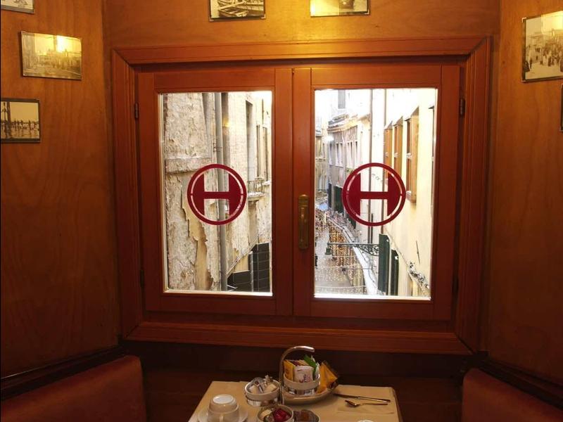 Coin repas confortable avec table ronde et deux fenêtres avec rideaux décoratifs.