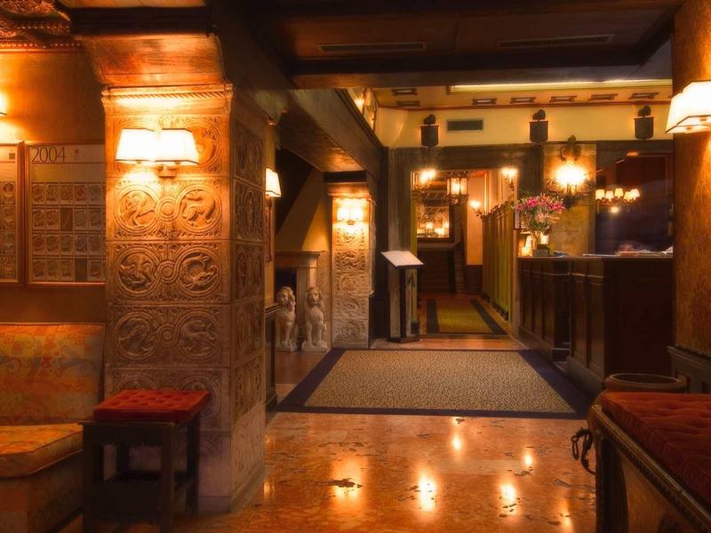 Ciepłe oświetlenie w historycznym lobby hotelowym z ozdobnymi elementami ścian i miejscami do siedzenia.