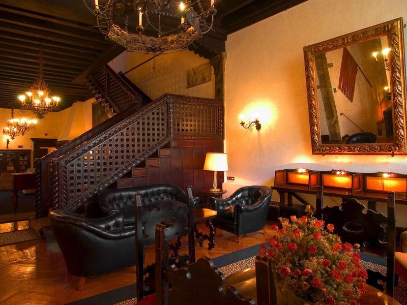 Przytulna lobby hotelowa z ciemnymi meblami skórzanymi, drewnianymi belkami i ciepłym światłem.