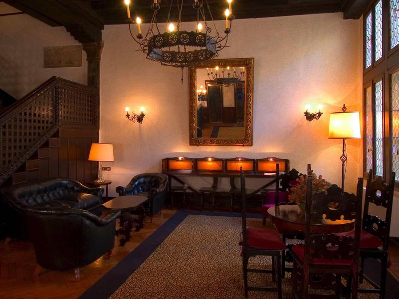 Przytulna część wypoczynkowa hotelu z drewnianą boazerią, sofami i ciepłym oświetleniem.