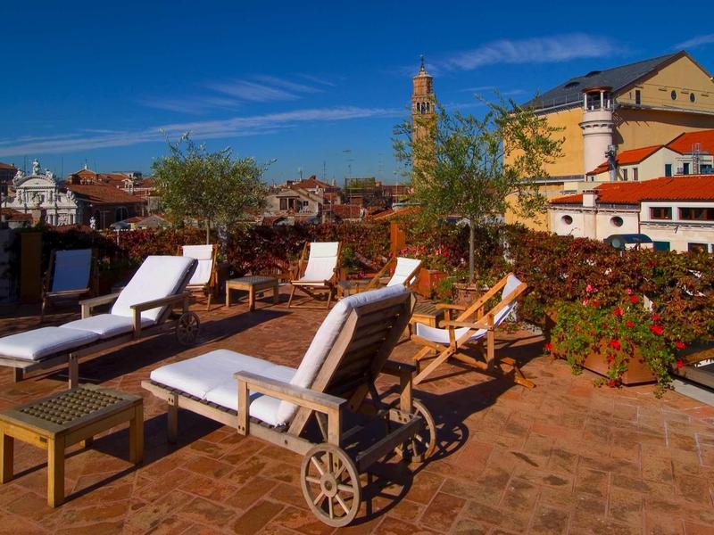 Taras słoneczny z leżakami pod niebieskim niebem z widokiem na miasto.