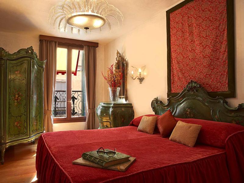 Elegancka sypialnia z czerwonym łóżkiem, antycznymi meblami i widokiem z okna.