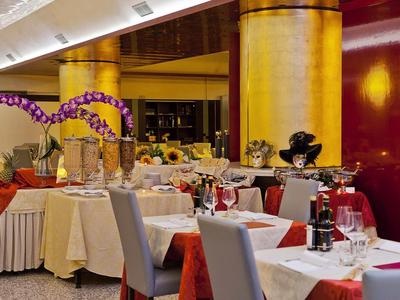 Elegantes Restaurant mit festlich gedeckten Tischen, roten Stühlen und goldfarbenen Säulen.