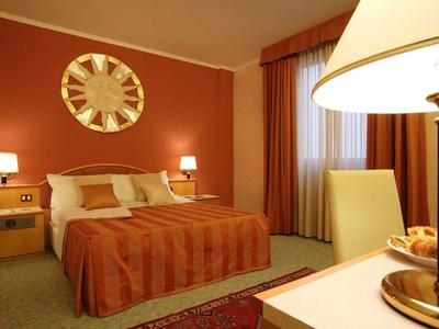 Gemütliches Schlafzimmer mit orangefarbenen Wänden, Bett, Nachttischen, Vorhängen und Tischlampe.