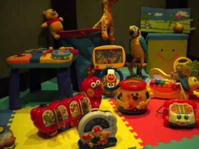 Buntes Kinderzimmer mit Spielzeug wie Tieren, Musikinstrumenten und Puzzlematten auf dem Boden.