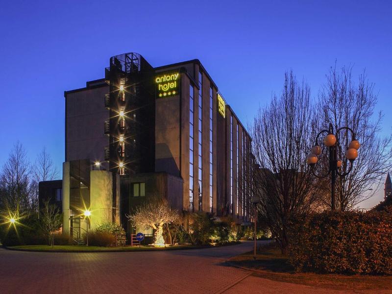 Ein mehrstöckiges Hotelgebäude bei Dämmerung mit beleuchteten Fenstern und klar blauem Himmel.