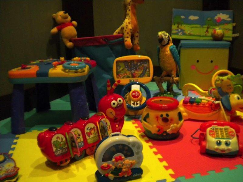 Buntes Kinderzimmer mit Spielzeug wie Tieren, Musikinstrumenten und Puzzlematten auf dem Boden.