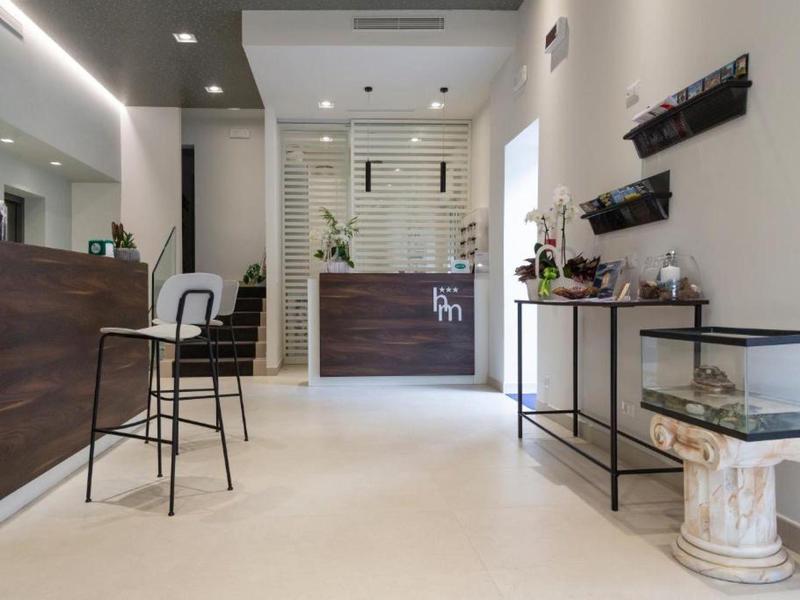 Heller, moderner Empfangsbereich mit dunklem Thekenmöbel, weißen Wänden und minimalistischer Deko.