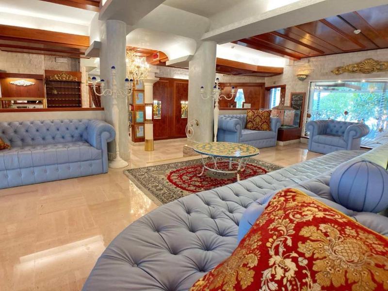 Großes Wohnzimmer mit blauen Sofas, Glas-Couchtisch, Teppich und Holzelementen an Decke und Möbeln.