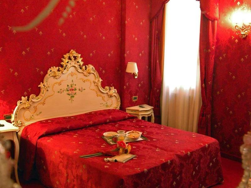 Chambre luxueuse avec papier peint rouge, couvre-lit rouge et lustre décoratif