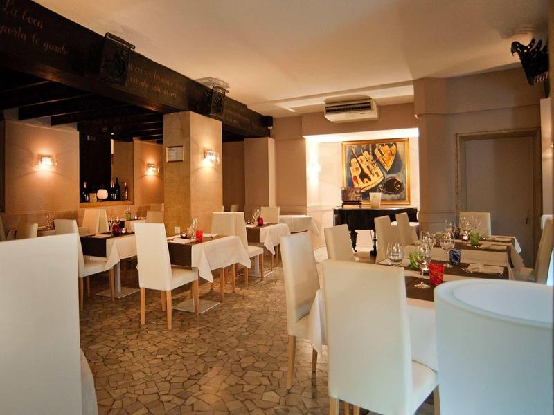 Salle à manger d'hôtel moderne avec chaises blanches et tables dressées.