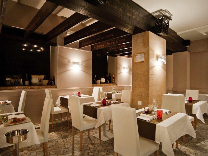 Restaurant élégant avec des chaises blanches et des tables dressées sous une lumière chaude.