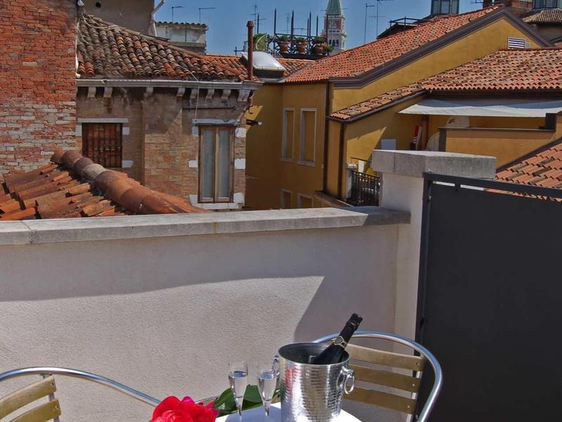 Petite table avec deux chaises sur balcon avec vieux toits en arrière-plan.