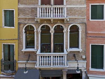 Facade of a multi-story building with arches and balcony in an urban area.