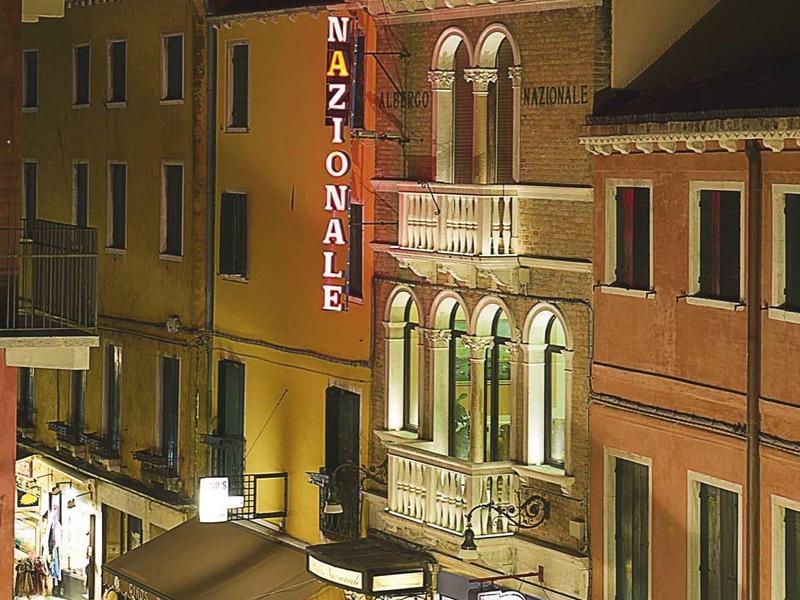 Illuminated Hotel Nazionale at a quiet street corner at night
