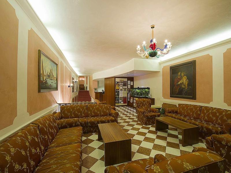 Large lounge with patterned sofas, small tables, and chandelier in hotel