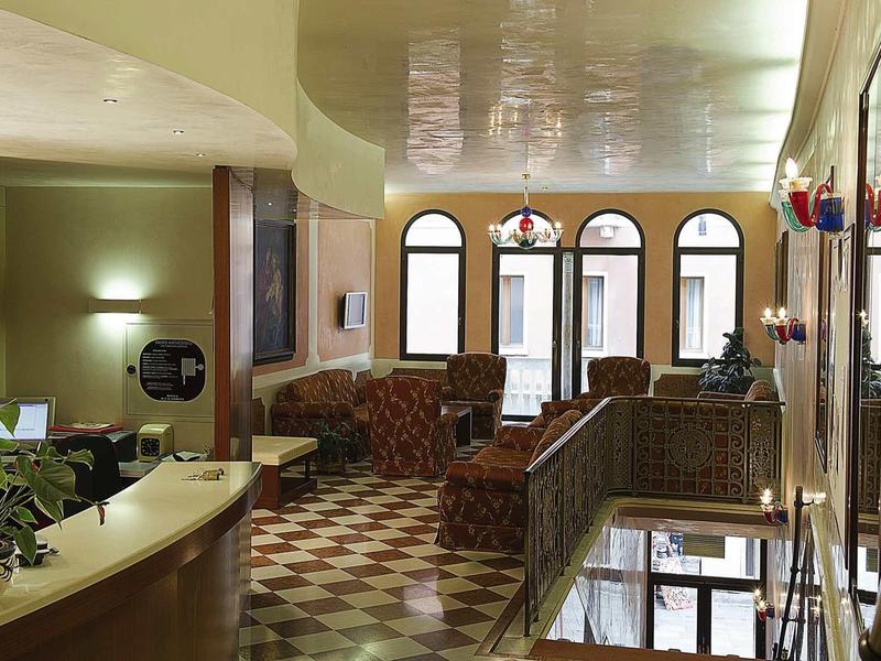 Brightly lit hotel lobby with seating and arched window front.