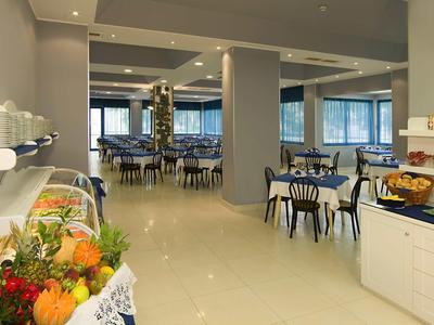 Modern dining area with set tables and fruit buffet in a hotel.