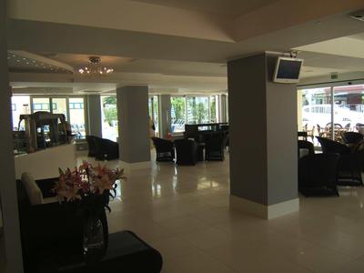 Moderner Hotel-Lobby-Bereich mit Polstersesseln, Tischen und großen Fenstern für Tageslicht.