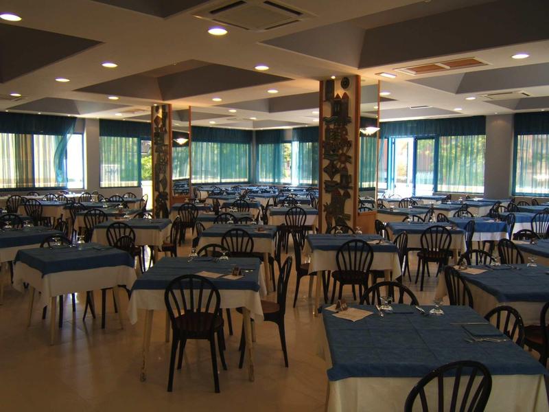 Large hotel dining room with many tables, chairs, and blue tablecloths.