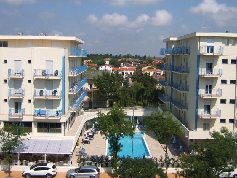 Two multi-story hotels with outdoor pool and blue sky in the background.