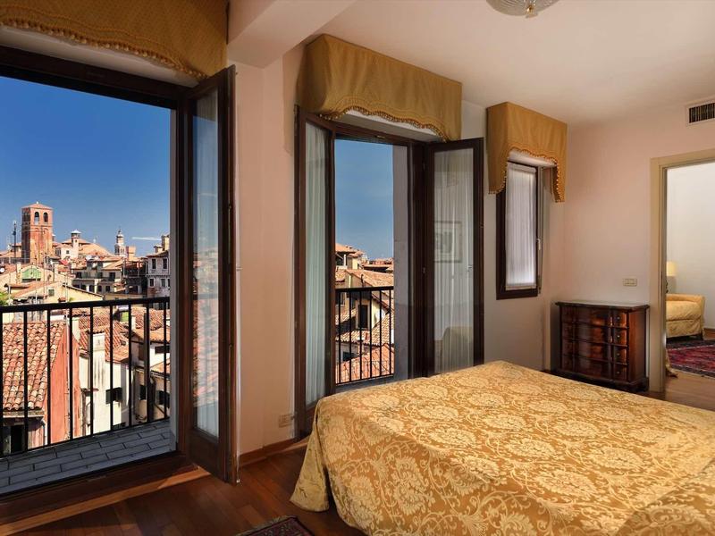 Ložnice s balkonem a výhledem na město za západu slunce.