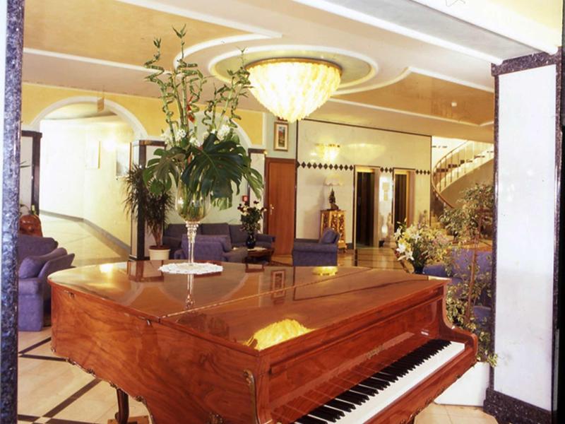 Elegant grand piano in stylish hotel lobby with warm lighting and decorative plants.