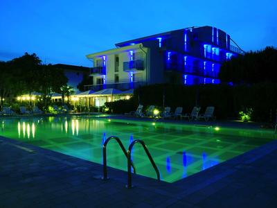 Piscina esterna illuminata davanti a un edificio di hotel moderno al crepuscolo