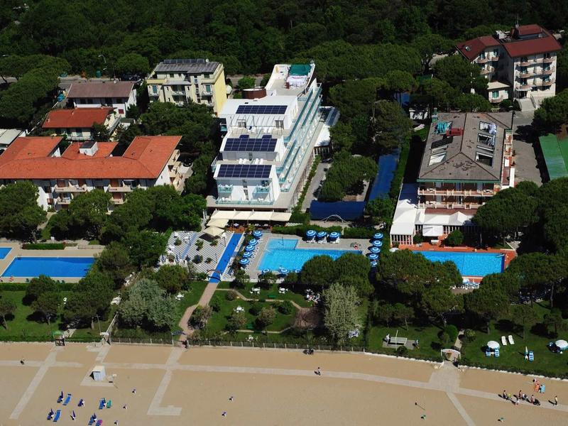 Vista di hotel con piscine vicino a una spiaggia sabbiosa e uno sfondo boscoso.
