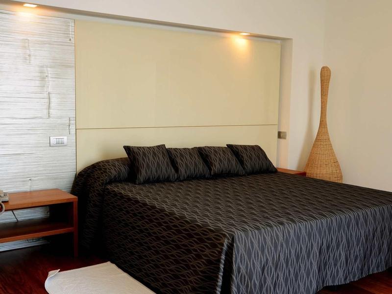 Camera moderna con letto grande, biancheria nera e testiera chiara.